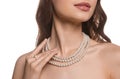 Young woman with elegant pearl jewelry on white background, closeup