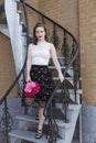 Young woman in elegant summer evening clothes standing in staircase waiting