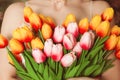 Young woman embraces a bouquet of tulips close-up without face