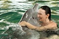 A young woman embraces a dolphin in the pool, swimming with dolphins Royalty Free Stock Photo