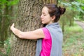 Young woman embraces tree