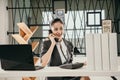 young woman employe sitting at office desk with laptop and talking on phone Royalty Free Stock Photo