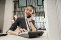 young woman employe sitting at office desk with laptop and talking on phone Royalty Free Stock Photo