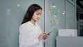 Young woman employee manager stands in office consulting client via internet using smartphone browsing web on social Royalty Free Stock Photo