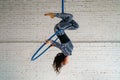 Young woman is engaged in aerial acrobatics on a white brick background. Royalty Free Stock Photo