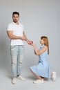 Young woman with engagement ring making marriage proposal to her boyfriend on grey background