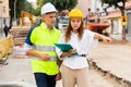 Young woman engineer on a construction site shows something to a man worker Royalty Free Stock Photo