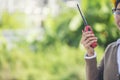 Young woman engineer or construction worker wearing safety hat helmet and holding portable radio with green nature background Royalty Free Stock Photo