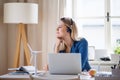 Young woman engineer with headphones sitting at the desk indoors in home office. Royalty Free Stock Photo