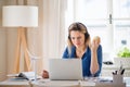 Young woman engineer with headphones sitting at the desk indoors in home office. Royalty Free Stock Photo