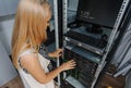 Young woman engineer It between the server racks in the data ce