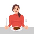 Young woman enjoy eating steak in the dish holding knife and fork as she is ready to eat Royalty Free Stock Photo