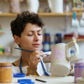 Young woman enjoy painting clay jug with paint after shaping and sculpturing earthenware potter jar