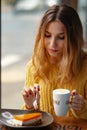 Young woman enjoying a cup of coffee and a slice of delicious ca