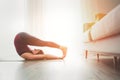 Young Woman enjoying evening yoga exercises doing Halasana pose at home living room near the big window. Active people and healthy Royalty Free Stock Photo