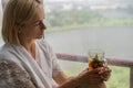 Young Woman Enjoying her morning tea, Looking Out the Rainy Window. Beautiful romantic unrecognizable girl drinking hot Royalty Free Stock Photo