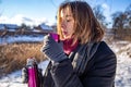 A young woman enjoys a hot drink from a thermos on a walk in winter. Royalty Free Stock Photo