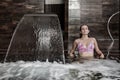 Young woman enjoying hydro massage in spa pool