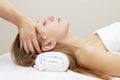 Young woman enjoying massage in spa salon. beautiful girl on a head and face massage procedure lies on white. Royalty Free Stock Photo