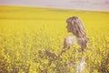 Young woman enjoying nature and sunlight in canola field, back view. Royalty Free Stock Photo