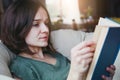 Young woman enjoying reading book in comfy sofa