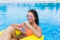 Young woman enjoying with rubber ring and cocktail in swimming pool Royalty Free Stock Photo