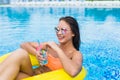 Young woman enjoying with rubber ring and cocktail in swimming pool Royalty Free Stock Photo