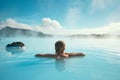 Young woman enjoying spa in hot springs in Iceland. Beautiful girl having fun in thermal bath on a backdrop of scenic Icelandic Royalty Free Stock Photo