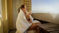 Young woman enjoying sunrise while drinking coffee on the balcony. People in morning, relaxing at home, enjoying city view Royalty Free Stock Photo