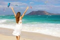 Young woman enjoying wind with raised arms and people kitesurfering, Corralejo Dunes beach, Fuerteventura, Canary Islands Royalty Free Stock Photo