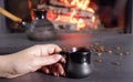 A young woman enjoys a coffee brewed in the traditional way in a ceramic dish. Close-up on hands against the background of burning Royalty Free Stock Photo