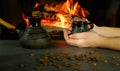 A young woman enjoys a coffee brewed in the traditional way in a ceramic dish. Close-up on hands against the background of burning Royalty Free Stock Photo