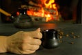 A young woman enjoys a coffee brewed in the traditional way in a ceramic dish. Close-up on hands against the background of burning Royalty Free Stock Photo