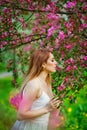 A young woman enjoys the fragrance of flowers in a spring blooming garden against the background of flowering trees. Young dreamy Royalty Free Stock Photo