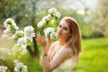 A young woman enjoys the fragrance of flowers in a spring blooming garden against the background of flowering trees. Young dreamy Royalty Free Stock Photo