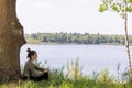 Tranquil Respite: Young Woman Resting Against Tree by the Lake