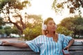 Young woman enjoys music through the headphones in the park Royalty Free Stock Photo