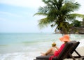 Young woman enjoys young coconut sitting on the beach Royalty Free Stock Photo