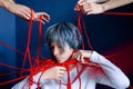 Young woman is entangled in red threads held by male and female hands. Concept of mental health, manipulation, public censure