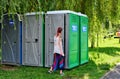 Young woman is entering a portable toilet