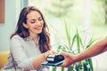 Young woman entering security pin in credit card reader while paying by credit card at cafe Royalty Free Stock Photo