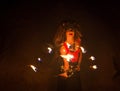 Young woman in ethnic jewelery and headdress holding before itself fan of flaming torches