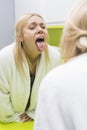 Young woman examining tongue in mirror