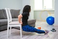 Young woman exercise at home. Sporty healthy lifestyle. Woman using a chair while doing workout Royalty Free Stock Photo