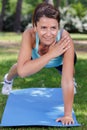 young woman exercising outdoors in one-armed plank position Royalty Free Stock Photo