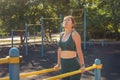 Young woman exercising on parallel bars on a street sports ground.