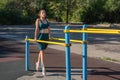 Young woman exercising on parallel bars on a street sports ground.