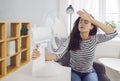 Young woman, exhausted from the summer heat, refreshing by an electric fan at home Royalty Free Stock Photo