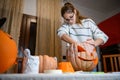 A girl carving big orange pumpkin into jack-o-lantern for Halloween holiday decoration at kitchen. Decoration for party Royalty Free Stock Photo