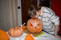 A girl carving big orange pumpkin into jack-o-lantern for Halloween holiday decoration at kitchen. Decoration for party Royalty Free Stock Photo